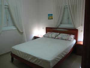 a bedroom with a bed with white sheets and windows at Ocean View Luxury apartment in Netanya