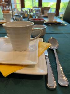 a white coffee cup on a plate on a table at Arduinna's Nest B&B in Neufchâteau
