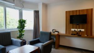 een woonkamer met twee stoelen en een televisie bij Heritage Suites in Mysore