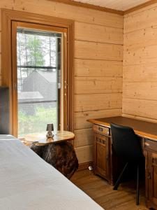 Un dormitorio con un escritorio y una cama y una ventana. en AureenHelmi, en Aurekoski