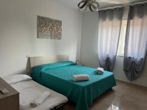 two beds in a bedroom with green sheets and towels at Rosa's House Casa Vacanze in Policoro