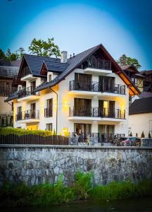 a large white building with balconies next to a river at Willa Zacisze Szczawnica 15 m2 in Szczawnica