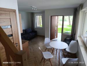 a living room with a table and white chairs at Domki nad Wierną Rzeką in Chęciny