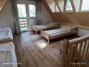 a attic room with two beds and windows at Domki nad Wierną Rzeką in Chęciny +10 photos