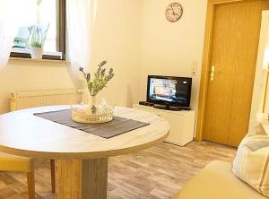 a living room with a table and a tv at Naturblick am Petersdorfer See in Petersdorf
