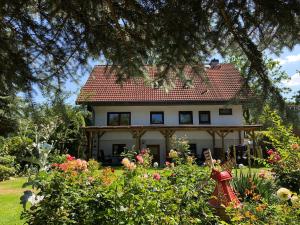 a white house with a red roof and some flowers at Naturblick am Petersdorfer See in Petersdorf