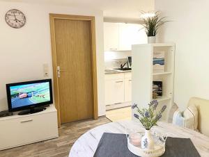 a living room with a table and a tv and a kitchen at Naturblick am Petersdorfer See in Petersdorf