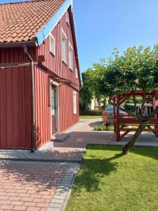 a red building with a tree next to a street at Ramus poilsis in Nida +1 photo