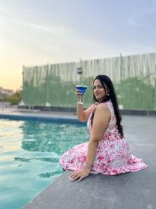 une femme assise près d'une piscine pour boire un verre dans l'établissement Katriya Hotel and Tower, à Hyderabad