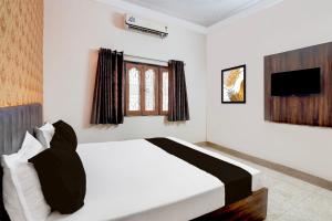 une chambre avec un lit blanc et une télévision dans l'établissement HOTEL O Happy Inn, à Jabalpur