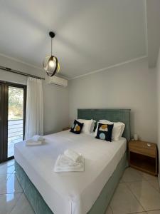 ニドリにあるElpida Luxury Apartments Suitesの白いシーツと枕が付いた大きなベッドのある寝室 +90枚の写真