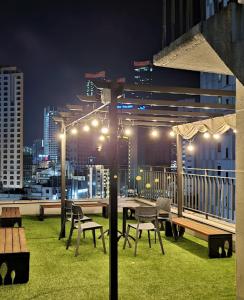een dakterras met een tafel, stoelen en verlichting bij Haeundae The Van Hotel in Busan