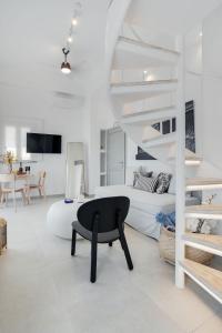 una habitación blanca con una silla negra y una cama en SantoView Suites, en Vourvoúlos