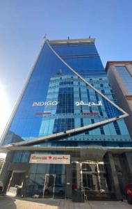 a large glass building with a sign in front of it at Indigo Apartments in Jeddah