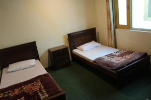 a bedroom with two beds and a window at Grandview Hotel skardu in Skardu