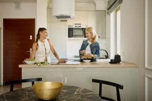 dos mujeres de pie en una cocina hablando en Waterlane Riverside - SPA, Pool, Gym & Parking by Downtown Apartments, en Gdansk