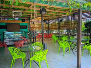 a restaurant with green tables and chairs in a room at The Air Inn Uttara in Dhaka