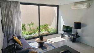 チャングーにあるHanupis Canggu Apartment Villaのソファと大きな窓のあるリビングルーム