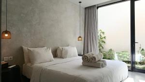 チャングーにあるHanupis Canggu Apartment Villaのタオルが敷かれた白いベッドのある寝室