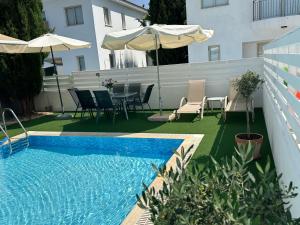 a swimming pool with an umbrella and chairs and a table at LC Palm Villa in Protaras