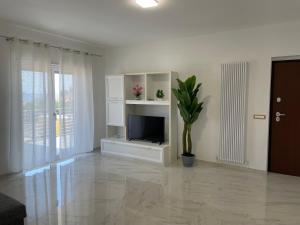 a white living room with a television and a plant at Villa Ale in Torregrotta