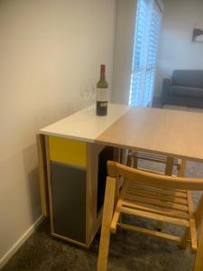 een tafel met een fles wijn en een stoel bij Ohope Coastal Escape in Ohope Beach +4 foto's