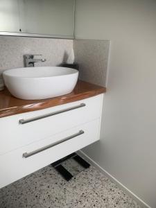 a bathroom with a white sink on a counter at Ohope Coastal Escape in Ohope Beach +6 photos