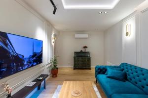 ein Wohnzimmer mit einem blauen Sofa und einem großen Fernseher in der Unterkunft The Luxury Loft in Bascarsija with free parking in Sarajevo