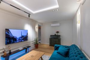 ein Wohnzimmer mit einem blauen Sofa und einem Flachbild-TV in der Unterkunft The Luxury Loft in Bascarsija with free parking in Sarajevo