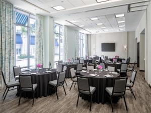 une salle de conférence avec des tables, des chaises et un écran dans l'établissement Hyatt Place West Palm Beach, à West Palm Beach