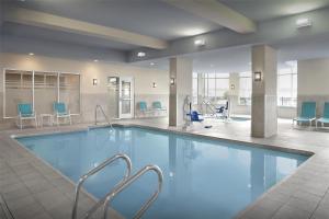a swimming pool in a hotel lobby with chairs and tables at Hilton Garden Inn Gallup in Gallup