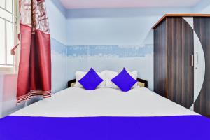 a bedroom with a large bed with blue pillows at SPOT ON Gayatri Comforts in Bengaluru