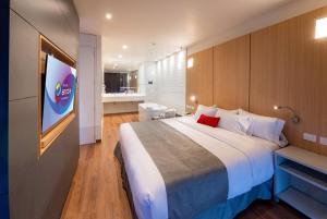 a bedroom with a large bed and a bathroom at Ramada Encore by Wyndham Guadalajara Aeropuerto in Guadalajara