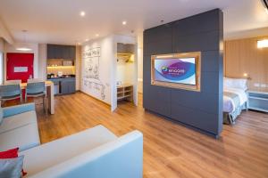 a hotel room with a bed and a tv on a wall at Ramada Encore by Wyndham Guadalajara Aeropuerto in Guadalajara