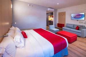 a bedroom with a large bed and a living room at Ramada Encore by Wyndham Guadalajara Aeropuerto in Guadalajara