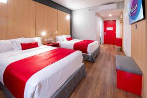 a hotel room with two beds and a red door at Ramada Encore by Wyndham Guadalajara Aeropuerto in Guadalajara