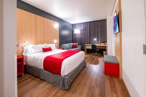 a hotel room with a large bed and a desk at Ramada Encore by Wyndham Guadalajara Aeropuerto in Guadalajara