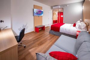 a hotel room with a bed and a desk at Ramada Encore by Wyndham Guadalajara Aeropuerto in Guadalajara
