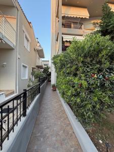 a walkway next to a building with bushes at Proluxe Apartments in Alexandroupoli