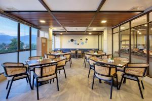 a restaurant with tables and chairs and windows at Aston Palu Hotel & Conference Center in Palu
