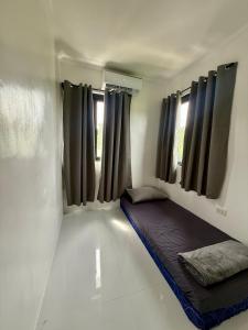 Una pequeña habitación con una cama en la esquina con ventanas. en Ace's Villa, Calapan, en Calapan 16 fotos más