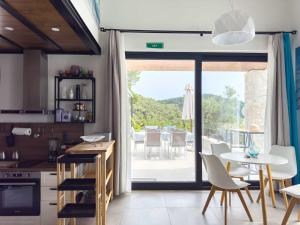 une cuisine avec une table et des chaises ainsi qu'une grande fenêtre dans l'établissement Allure Luxury Villas 3&4 Serenity Retreat, à Skiathos Chora