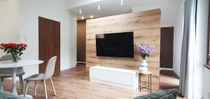 a living room with a television and a table and chairs at Willa Matejki - Apartament 8b in Przemyśl
