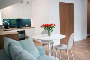 ein Wohnzimmer mit einem Tisch und einer Vase mit roten Blumen in der Unterkunft Willa Matejki - Apartament 8b in Przemyśl + 2 Fotos