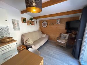 a small living room with a couch and a tv at Maison avec jardinet, piscine commune à Lacanau océan in Lacanau-Océan