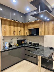Una cocina con gabinetes de madera y encimera de granito. en Luxury family properties in Centaurus, Blue area, F10, F11, Park, en Islamabad