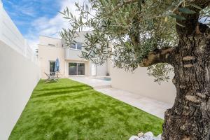 ein weißes Haus mit einem Baum im Hof in der Unterkunft Villa climatisée avec piscine et stationnements in Vendargues