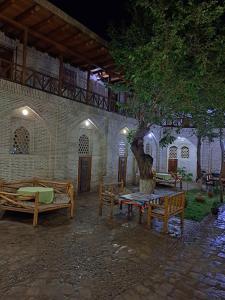 une cour avec des bancs, un arbre et un bâtiment dans l'établissement Ohun saray Historical Museum hotel XIX century Best cheap in old sity Bukhara boasts a wealth of historical monuments, reflecting its rich history as a major Silk Road city, à Boukhara