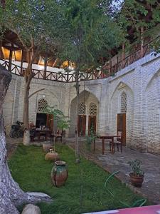 - un jardin avec un arbre, une table et des chaises dans l'établissement Ohun saray Historical Museum hotel XIX century Best cheap in old sity Bukhara boasts a wealth of historical monuments, reflecting its rich history as a major Silk Road city, à Boukhara