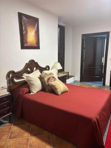 a bedroom with a bed with red sheets and pillows at Casa cubo in Alhama de Granada